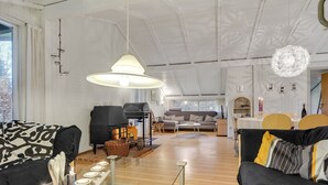 Un vaste espace de vie comprenant une grande fenêtre, une cheminée, un canapé et une table à manger.