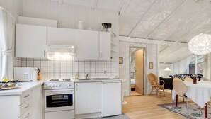 Une cuisine moderne avec des meubles blancs, une cuisinière et un évier. On y trouve également un coin repas avec une table et des chaises.