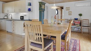 Une cuisine spacieuse avec des meubles de rangement en bois, un coin repas avec une table et des chaises en bois, et une horloge traditionnelle accrochée au mur.