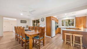 Une cuisine moderne avec des meubles en bois, un réfrigérateur et un coin repas comprenant une table et des chaises.