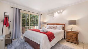 Ein Hotelzimmer mit Bett, Nachttisch, Lampe, Heizung und einem Fenster mit Vorhängen.