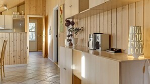 Una cocina moderna con paneles de madera, suelo de baldosas y encimera con electrodomésticos.