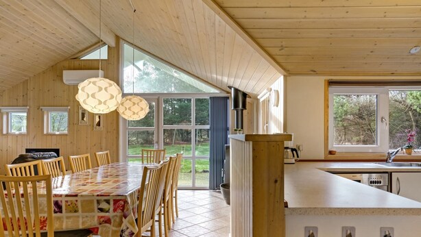 Un interior de madera con comedor, cocina y ventanas amplias.