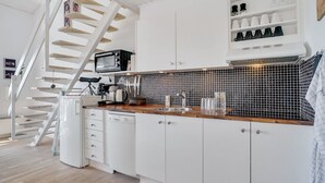 A modern kitchen with white cabinets, a wooden staircase, and a tiled backsplash. - "Idunn" - 100m to the fjord by Interhome (Vestervig)