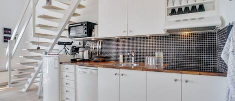 Een koelkast, een vaatwasser, kookgerei, borden en bestek