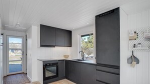 A modern kitchen with black cabinets, a built-in oven, and a window. - "Gillis" - 900m from the sea by Interhome (Ringkøbing)
