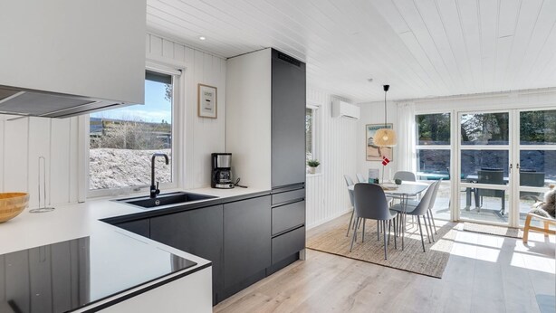 A modern kitchen with a large island, a dining area with a table and chairs, and a view of the outdoors. - "Gillis" - 900m from the sea by Interhome (Ringkøbing)