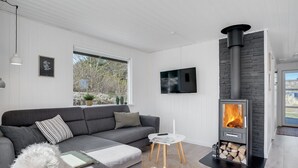 A modern living room with a grey sofa, a small white table, and a wood-burning stove. - "Gillis" - 900m from the sea by Interhome (Ringkøbing)