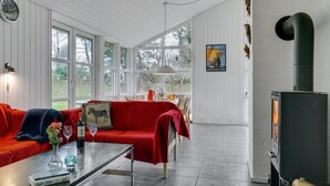 Ein gemütliches Wohnzimmer mit einem roten Sofa, einem Glastisch und einem Kamin.