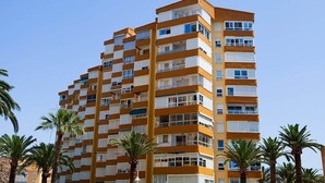 A multi-story hotel with a distinctive orange and white facade, balconies, and palm trees in the foreground. - Apartment With see View in Algarrobo. 20 Meters to the Beach (Algarrobo - Costa)