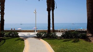 A paved pathway leading to a beach with palm trees, a lamp post, and a view of the sea. - Apartment With see View in Algarrobo. 20 Meters to the Beach (Algarrobo - Costa)