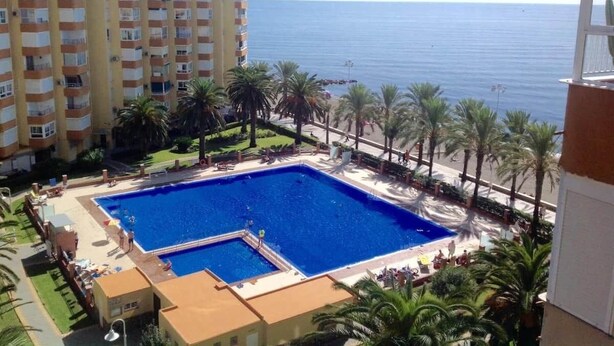 A hotel with a large pool, a view of the sea, and palm trees. - Apartment With see View in Algarrobo. 20 Meters to the Beach (Algarrobo - Costa)