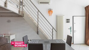 Ein modernes Zimmer mit Esstisch, Stühlen, einer Treppe und einer Tür.