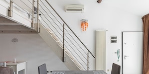 Ein modernes Zimmer mit Esstisch, Stühlen, einer Treppe und einer Tür.