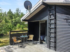 A wooden cabin with a deck, satellite dish, and outdoor seating. - "Heike" - 1.3km from the sea by Interhome (Blokhus)
