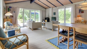 A spacious living area with a wooden ceiling, large windows, a fireplace, and a dining table. - "Heike" - 1.3km from the sea by Interhome (Blokhus)