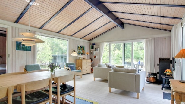 A spacious living area with a high ceiling, wooden beams, a dining table with chairs, a sofa, and a fireplace. - "Heike" - 1.3km from the sea by Interhome (Blokhus)