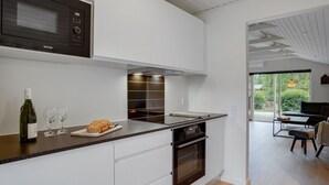 Een moderne keuken met witte kasten, een ingebouwde magnetron en een roestvrijstalen afzuigkap.