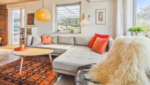 Een moderne woonkamer met een hoekbank, een ronde salontafel en een kamerbreed tapijt met een patroon.