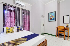 A bedroom with a bed, curtains, a desk, a chair, and a painting on the wall. - OYO Life 92575 Zazi Homestay (Depok)