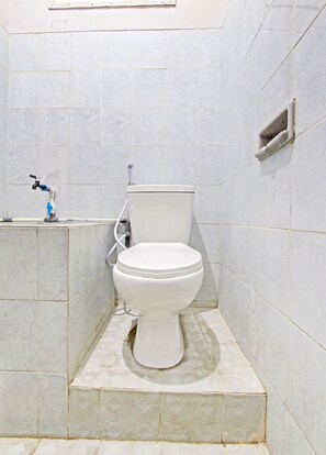 A bathroom with a toilet, a hand dryer, and a towel rack. - OYO Life 92575 Zazi Homestay (Depok)