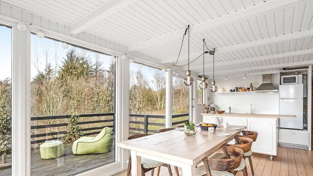 Una cocina moderna con armarios blancos, una mesa de comedor de madera y vistas al exterior.