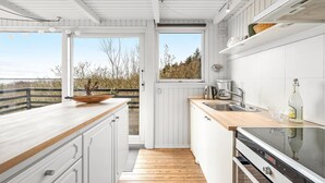 Una cocina moderna con armarios blancos, encimera de madera y vistas al exterior.