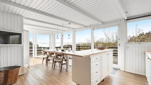 Una cocina amplia con una isla grande, suelo de madera y vista a la playa.