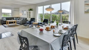 Un soggiorno moderno con zona pranzo, ampie finestre e vista sull'esterno.