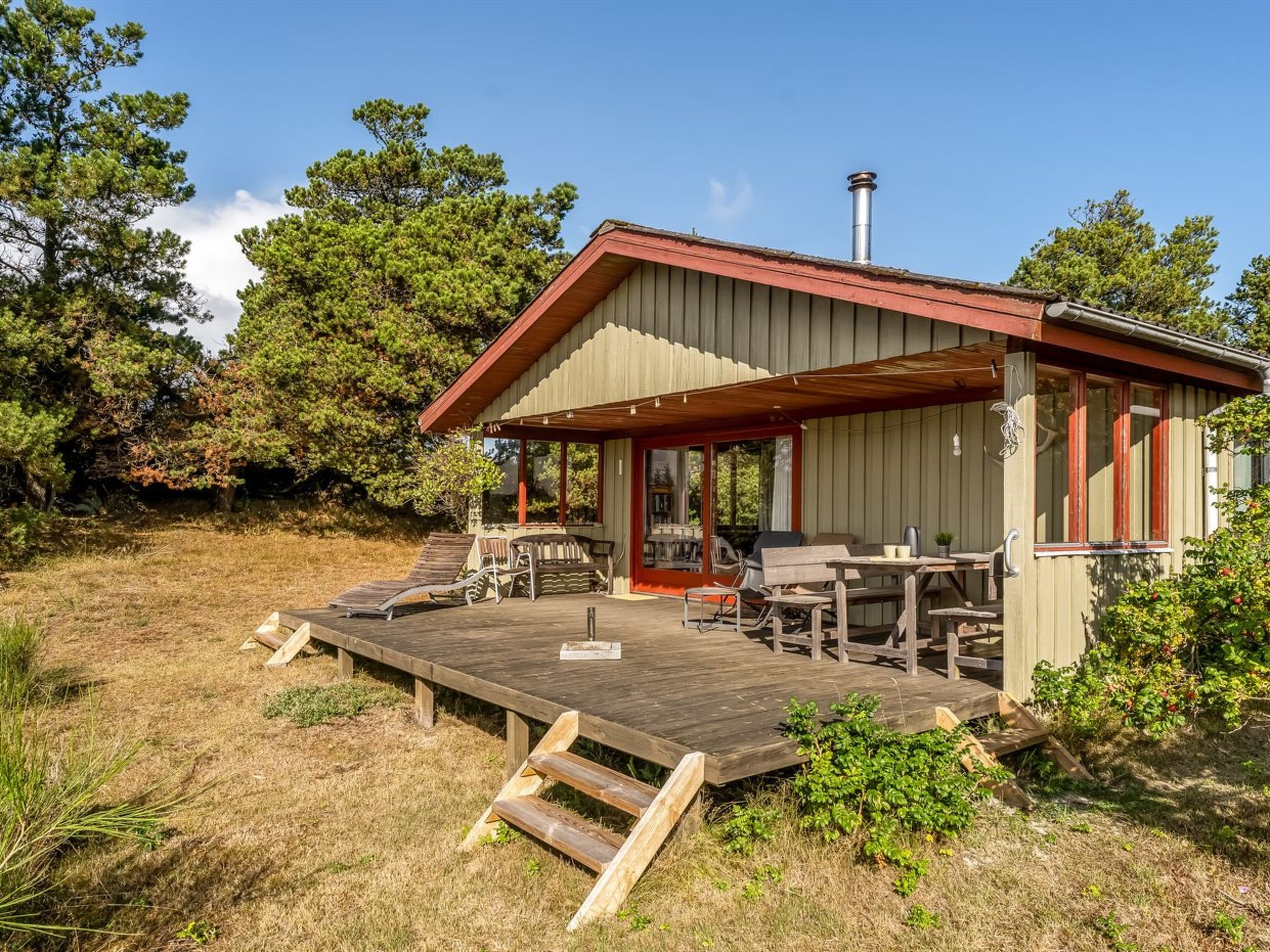 A cabin with a wooden deck, outdoor seating, and a chimney.