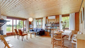 Une pièce spacieuse dotée d’un plancher en bois, d’un canapé bleu, d’une table à manger avec des chaises et d’une bibliothèque remplie de livres.