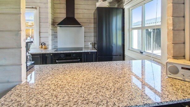 A kitchen with granite countertops, a stainless steel range hood, and a window with a view of the outside.