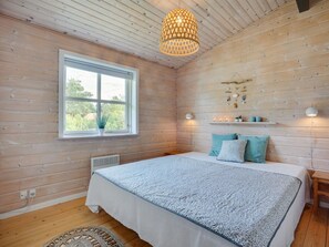 A bedroom with a large bed, wooden walls, a window, and a hanging light fixture. - "Botwith" - 400m from the sea by Interhome (Ørsted)