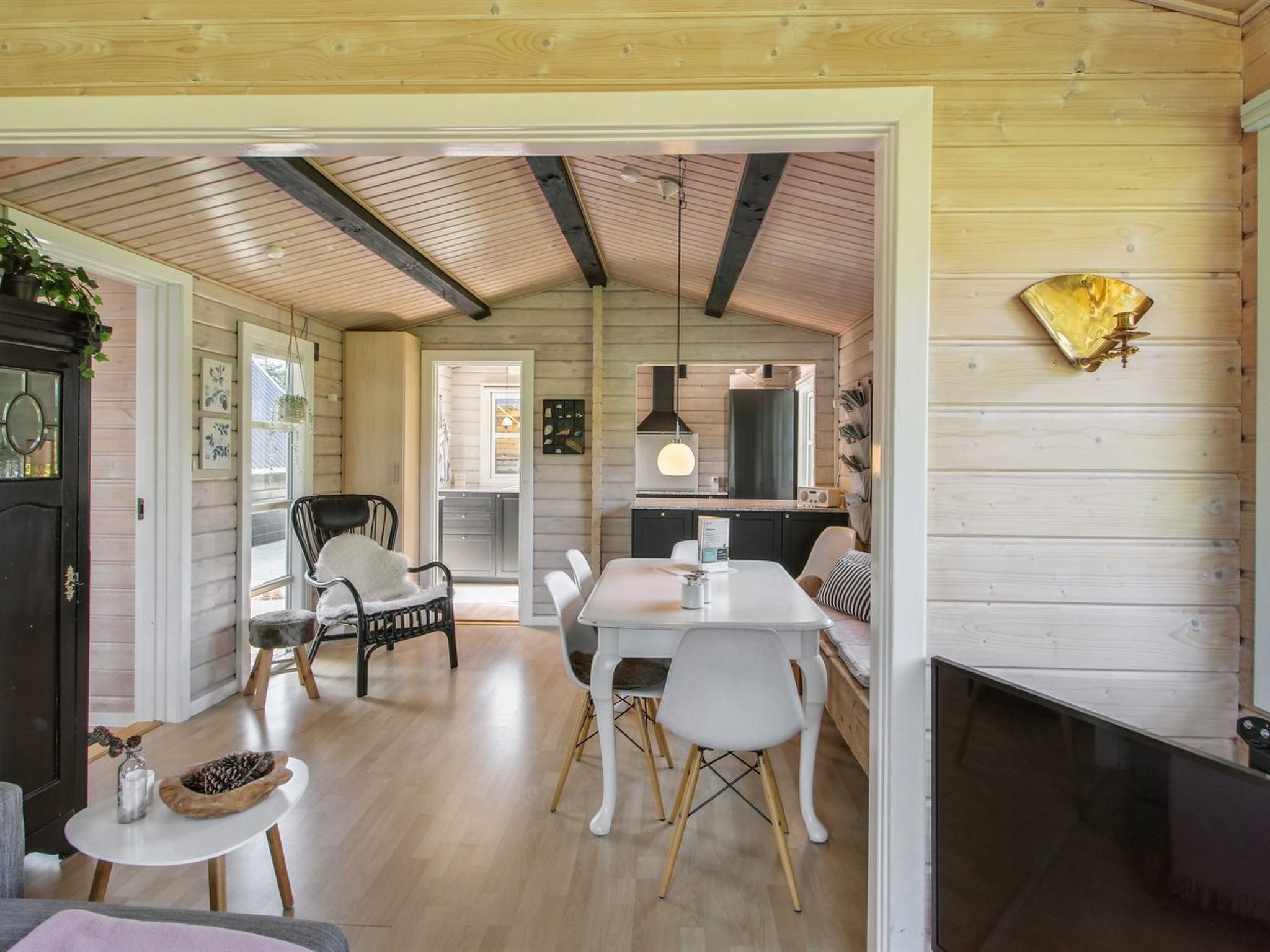 Um interior acolhedor com área de refeições, cozinha e teto de madeira.