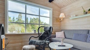 A cozy room with a large window, a fireplace, a sofa, a chair, and a small table.