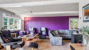 A modern living room with a purple accent wall, leather sofas, a coffee table, and a wooden floor. - "Merrit" - 4.6km to the fjord by Interhome (Hemmet)