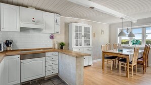 A modern kitchen with white cabinetry, a wooden countertop, and a dining area with a table and chairs. - "Merrit" - 4.6km to the fjord by Interhome (Hemmet)