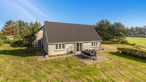 A single-story house with a tiled roof, a patio with outdoor furniture, and a grassy yard. - "Merrit" - 4.6km to the fjord by Interhome (Hemmet)