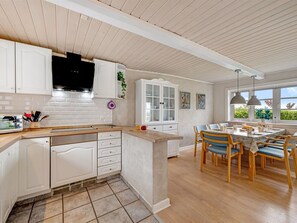 A kitchen with white cabinetry, a central island, and a dining area with blue chairs. - "Merrit" - 4.6km to the fjord by Interhome (Hemmet)