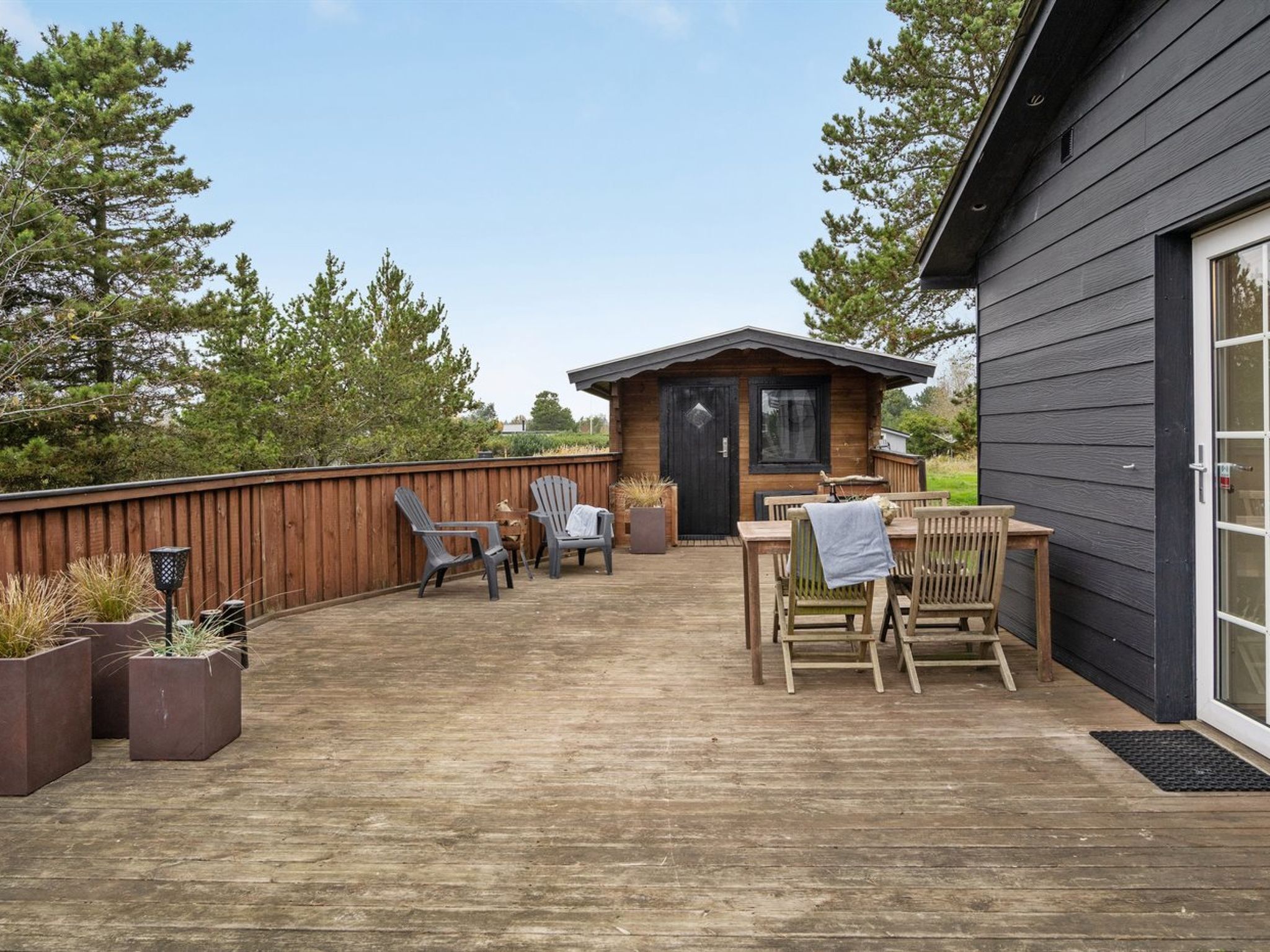 A wooden deck with outdoor furniture, a small wooden building, and a wooden fence.
