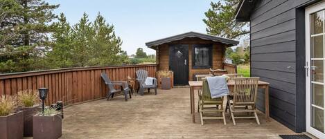 A wooden deck with outdoor furniture, a small wooden building, and a wooden fence.