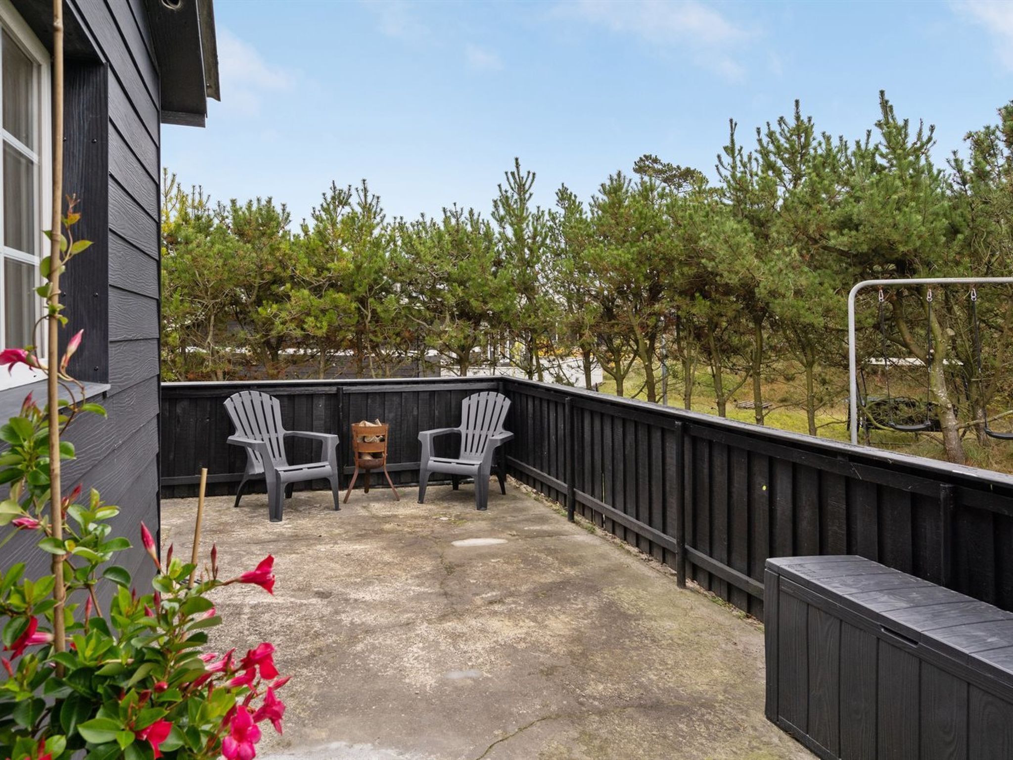 Une terrasse avec deux fauteuils Adirondack, une petite table et une plateforme en bois.