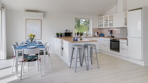 A modern kitchen with white cabinetry, a wooden island, and bar stools. - "Rickmer" - 200m from the sea by Interhome (Ebeltoft)