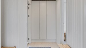 A narrow hallway with a wooden bench, a patterned rug, and a door leading to a room with white walls and a ceiling light. - "Rickmer" - 200m from the sea by Interhome (Ebeltoft)