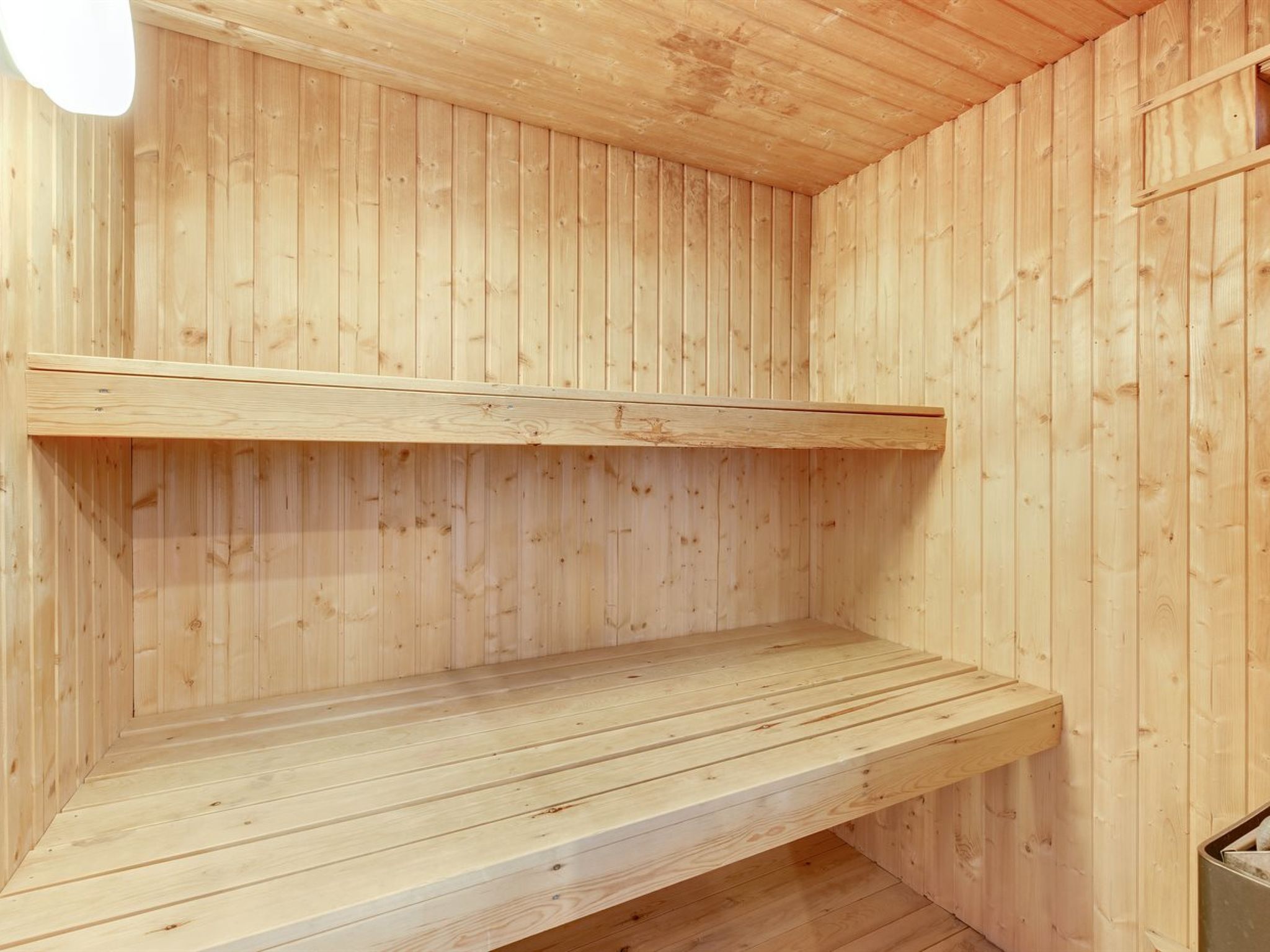 Ein rustikaler Innenraum mit zwei Holzbänken und einer schrägen Decke.