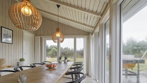 A dining area with a wooden table, black chairs, and two hanging light fixtures.