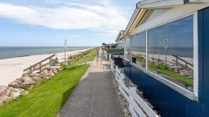 Un paseo marítimo que conduce a un edificio con grandes ventanales con vistas a la playa.