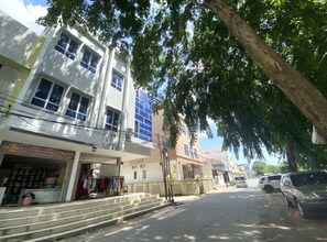 A street view with a building featuring a ground floor shop and upper residential or office spaces. - Hotel O Happy 777 (Batam)