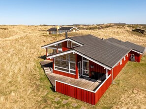 Una casa moderna con fachada roja, ventanas grandes y techo plano.