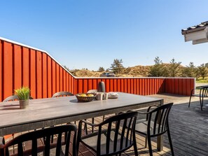 Un área de comedor al aire libre con una mesa, sillas, una planta en maceta y una cesta de pan.